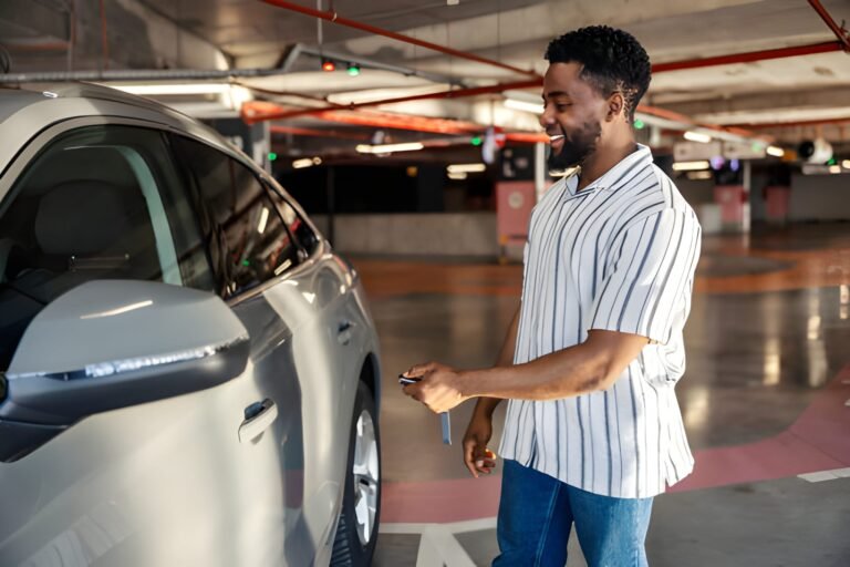 Smiling black man is locking car door in garage.